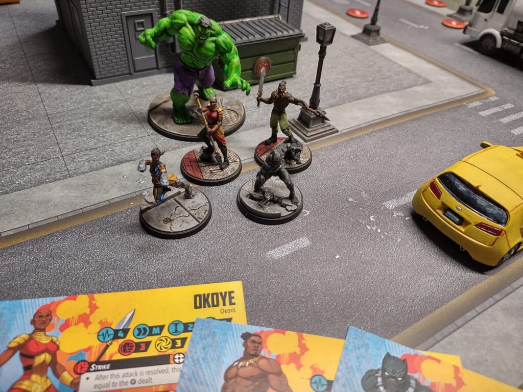 Minis of Marvel characters including Hulk, Black Panther, and Okoye ready to dive into action on urban terrain. 
